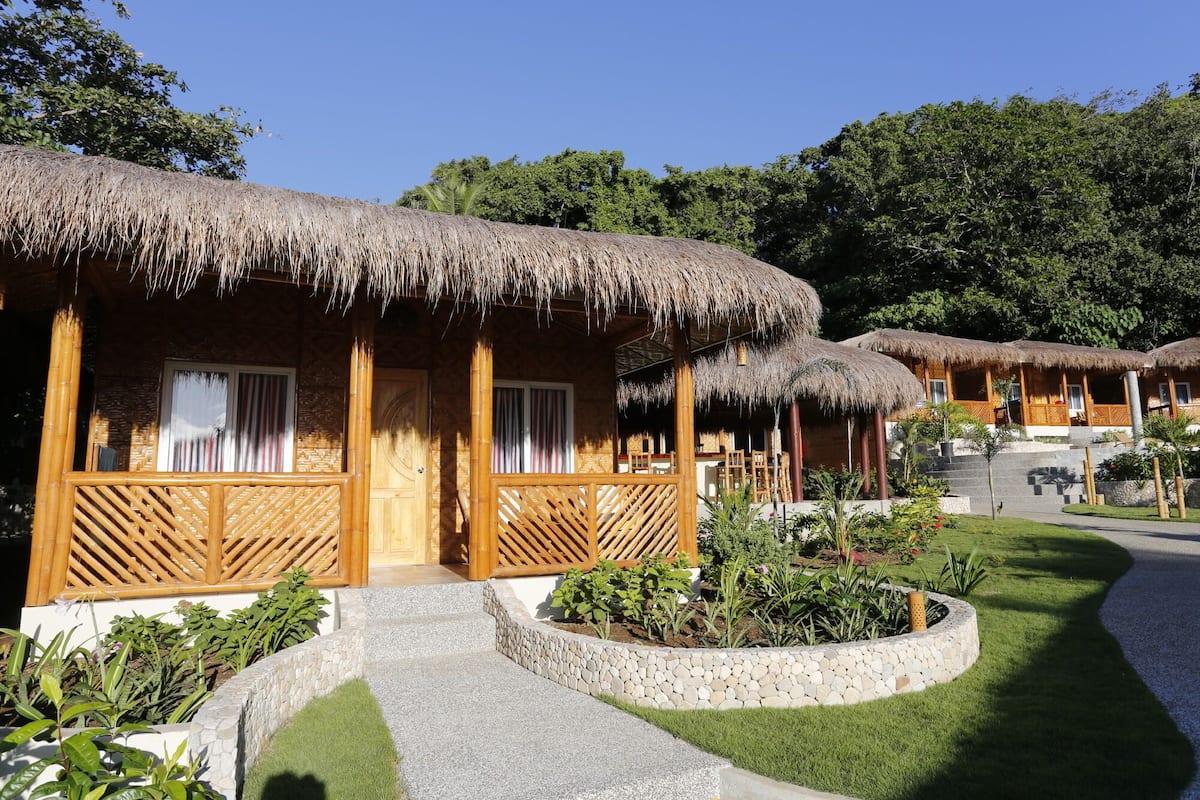 Una hilera de casas de campo con techos de paja, balcones de madera y un camino de piedra que las conduce.