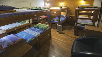 Une chambre de dortoir avec des lits superposés, un plancher en bois et un radiateur.