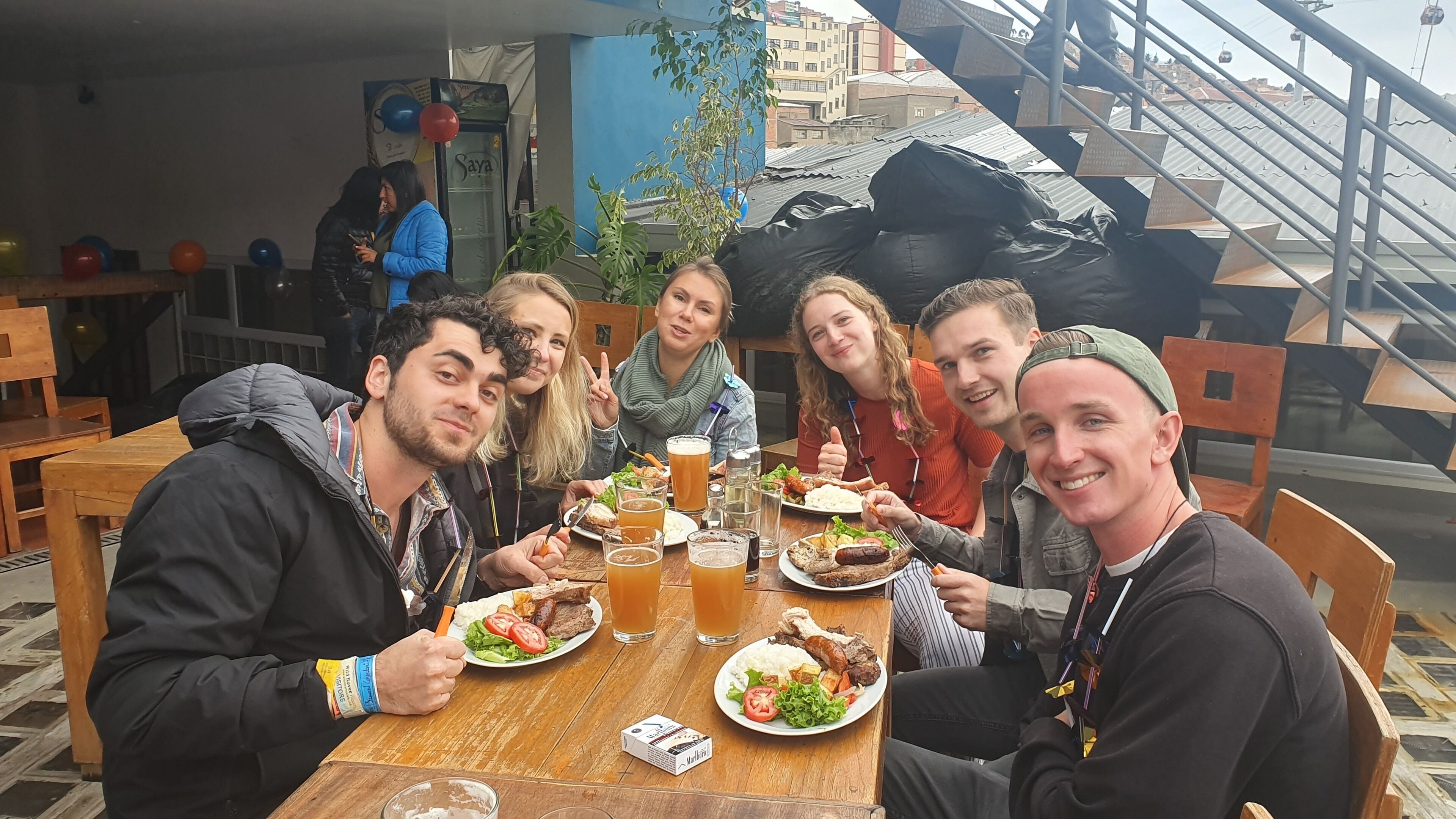 A group of people dining at an outdoor restaurant with a view of the cityscape.