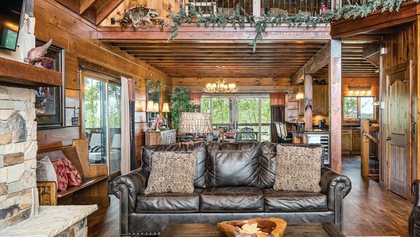 A spacious living area with a leather sofa, a stone fireplace, and a wooden coffee table.