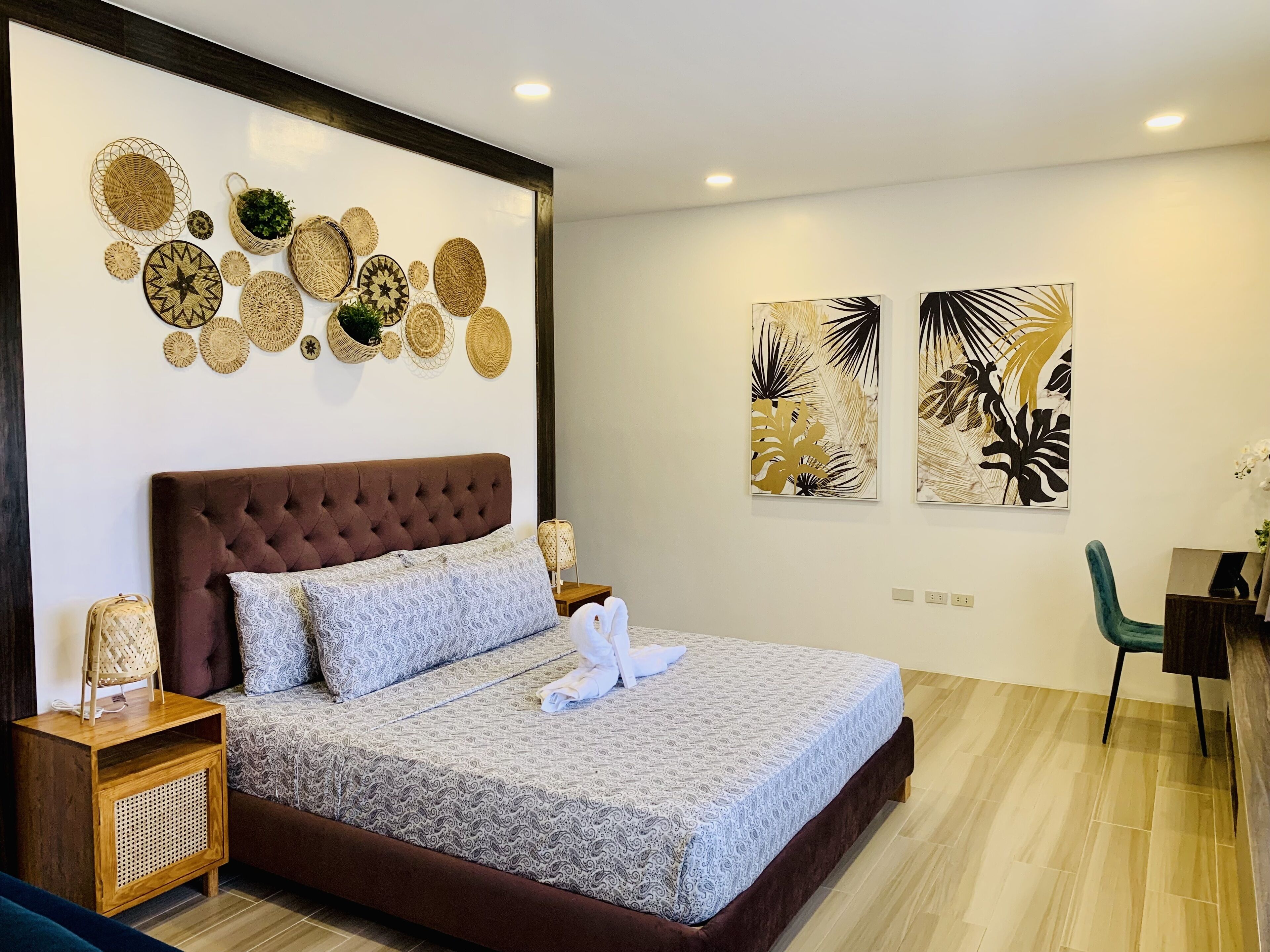 Un dormitorio ordenado con cabecera capitonada, ropa de cama estampada y decoración de pared.