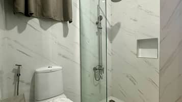 Un baño moderno con ducha envuelta en cristal, inodoro y barra para toallas.