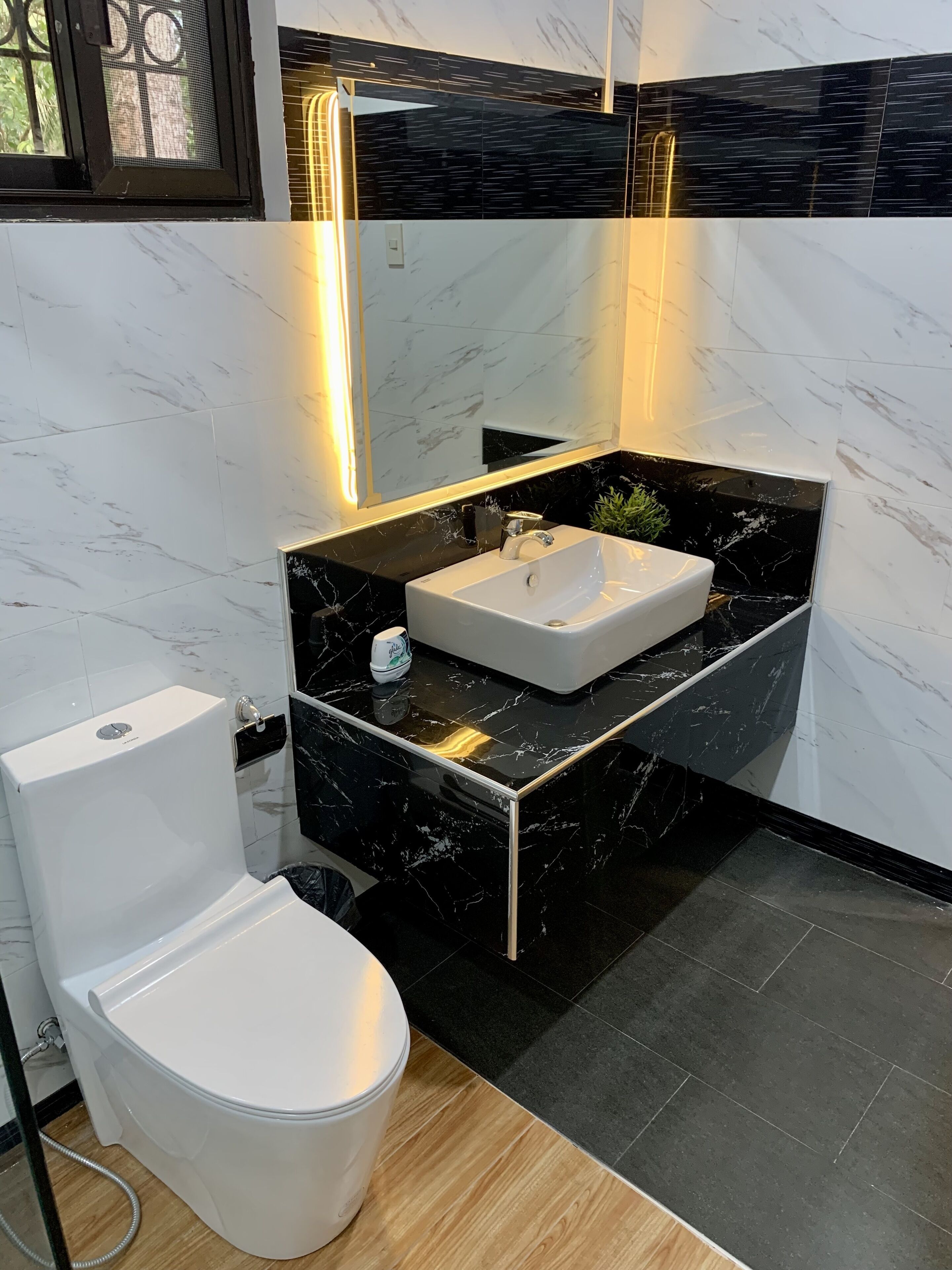 A modern bathroom with a white toilet, a white sink, and a black marble countertop.