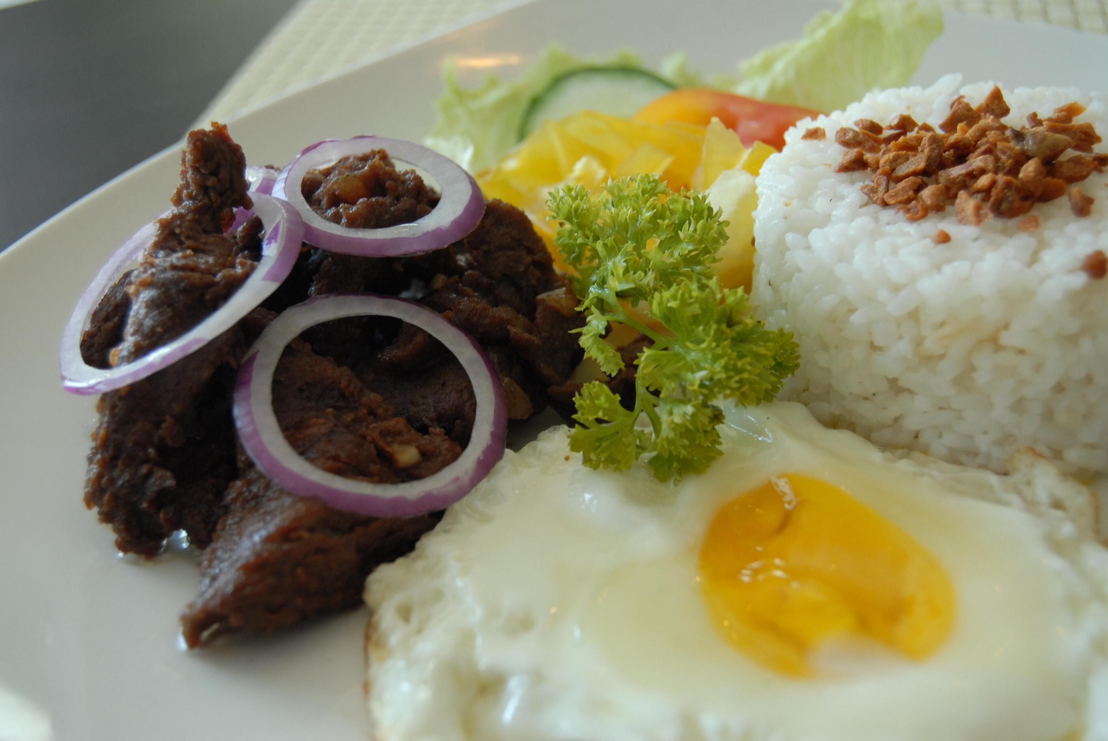 A plate of food with rice, beef, egg, and vegetables.