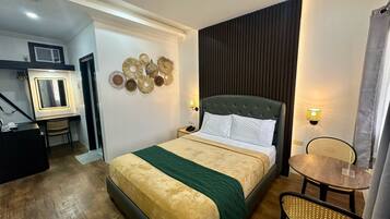 Une chambre d’hôtel comprenant un lit, une table de chevet, une chaise et une petite table avec une lampe.