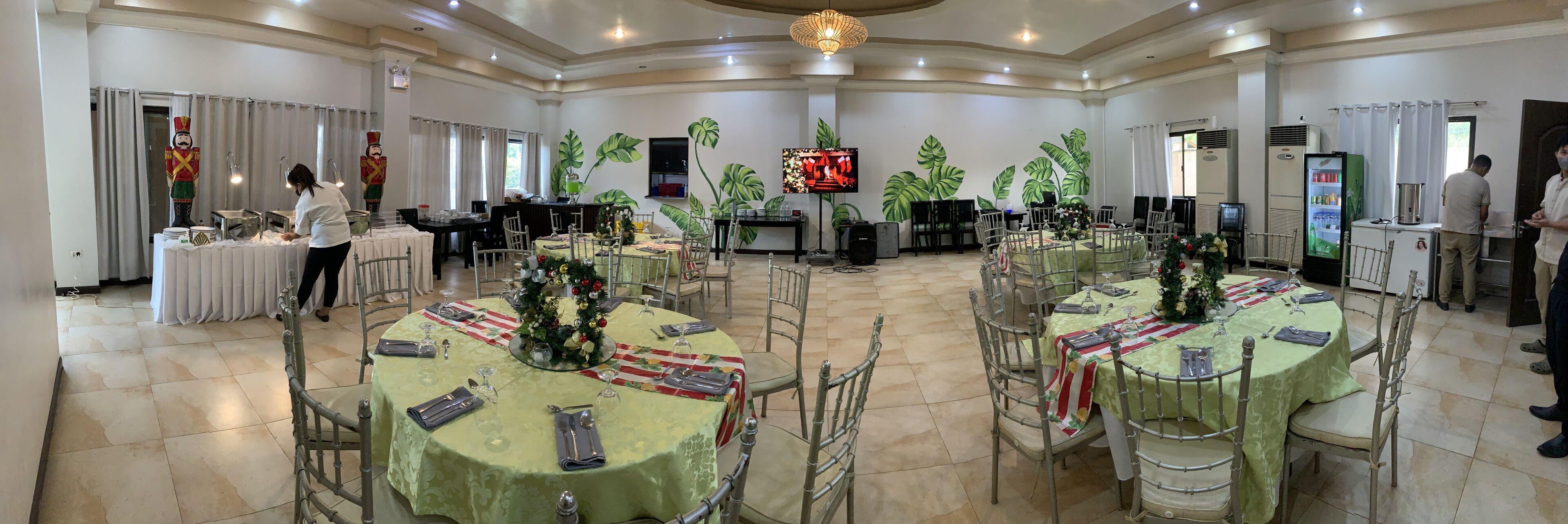A banquet hall with round tables, chairs, and a Christmas tree.