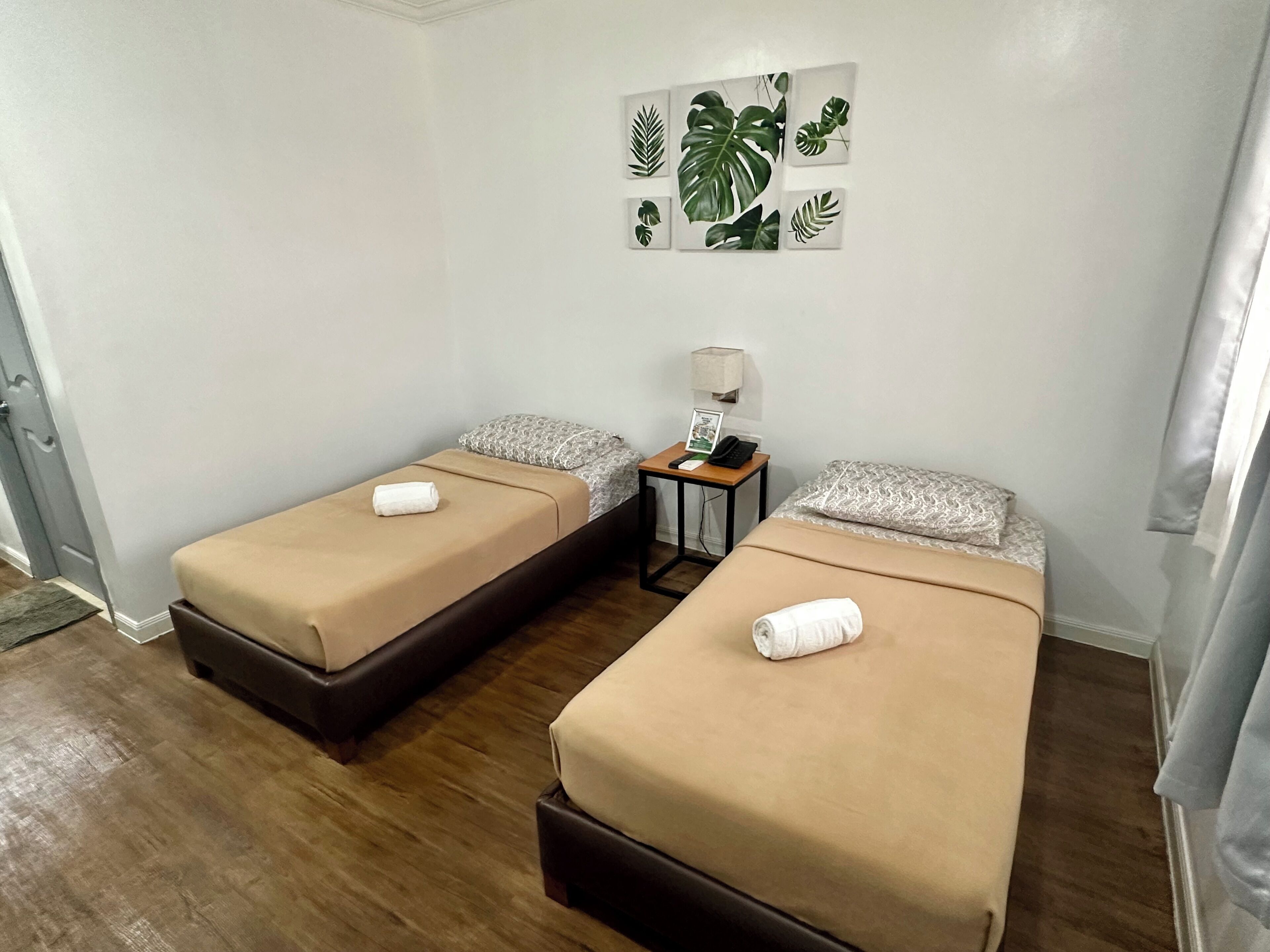 Una habitación con dos camas individuales, una mesita con lámpara y una obra de arte en la pared.