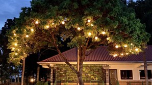 A house with a covered porch, a tree with hanging lights, and a red-tiled roof.
