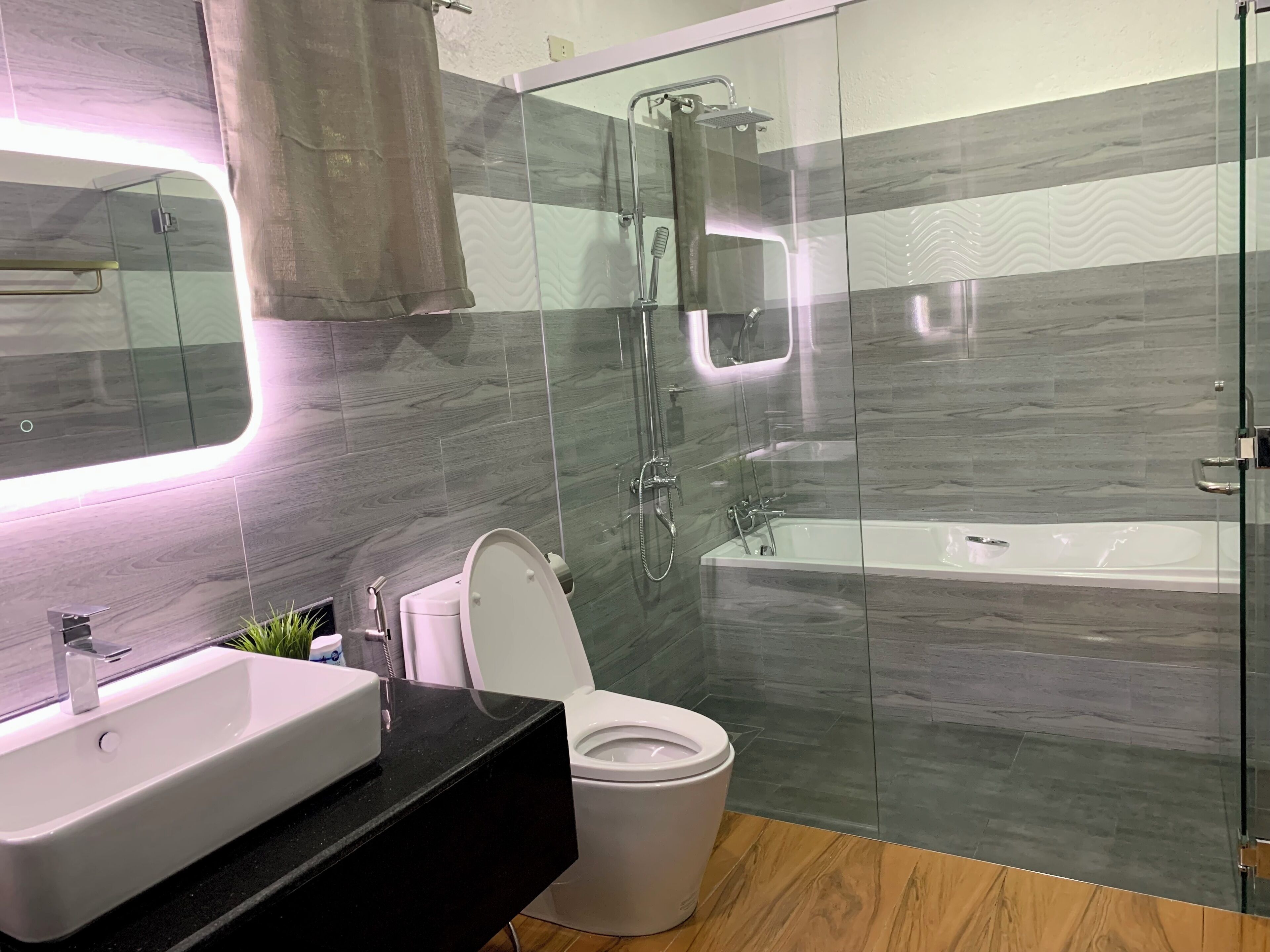 Un baño moderno con ducha de vidrio, bañera, inodoro y lavamanos.