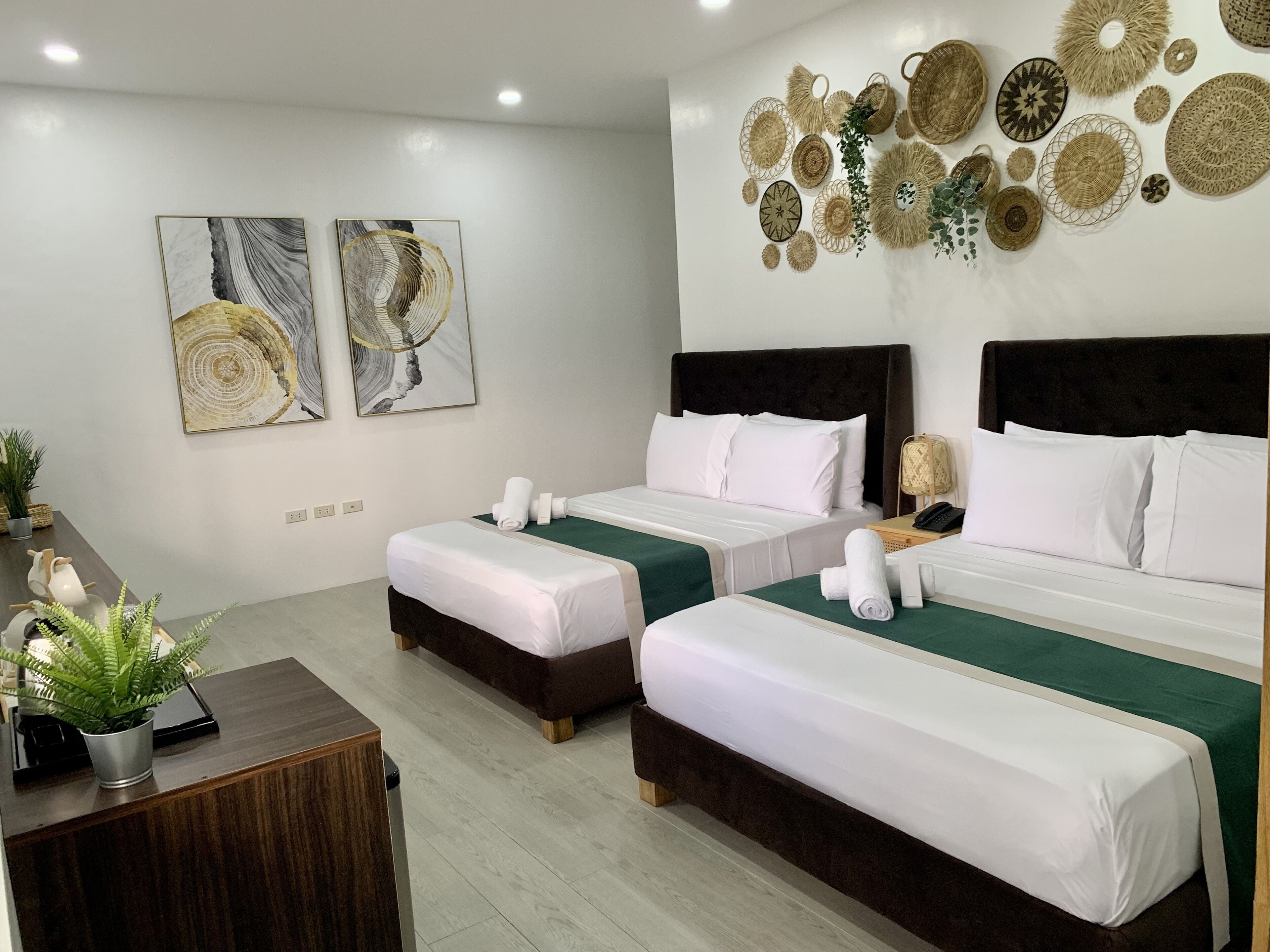 A hotel room with two beds, a desk, and wall art.
