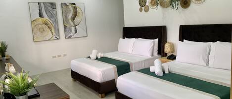 Habitación de hotel con dos camas, un escritorio y decoración en la pared.