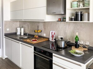 A modern kitchen with white cabinetry, a stainless steel range hood, a double sink, and a wooden countertop. - Sandpiper (Wendtorf)