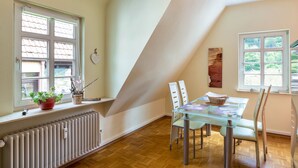 A dining area with a table and chairs, a radiator, and windows with blinds.