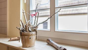 Un rustico vaso di legno con rami e una decorazione a forma di farfalla su un davanzale.