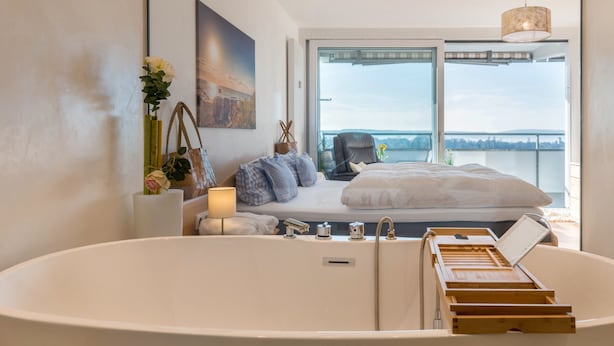Une chambre d’hôtel moderne dotée d’une grande baignoire, d’un lit avec vue et d’une grande fenêtre.