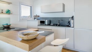 Une cuisine moderne avec un plan de travail en bois, une chaise blanche et une fenêtre.