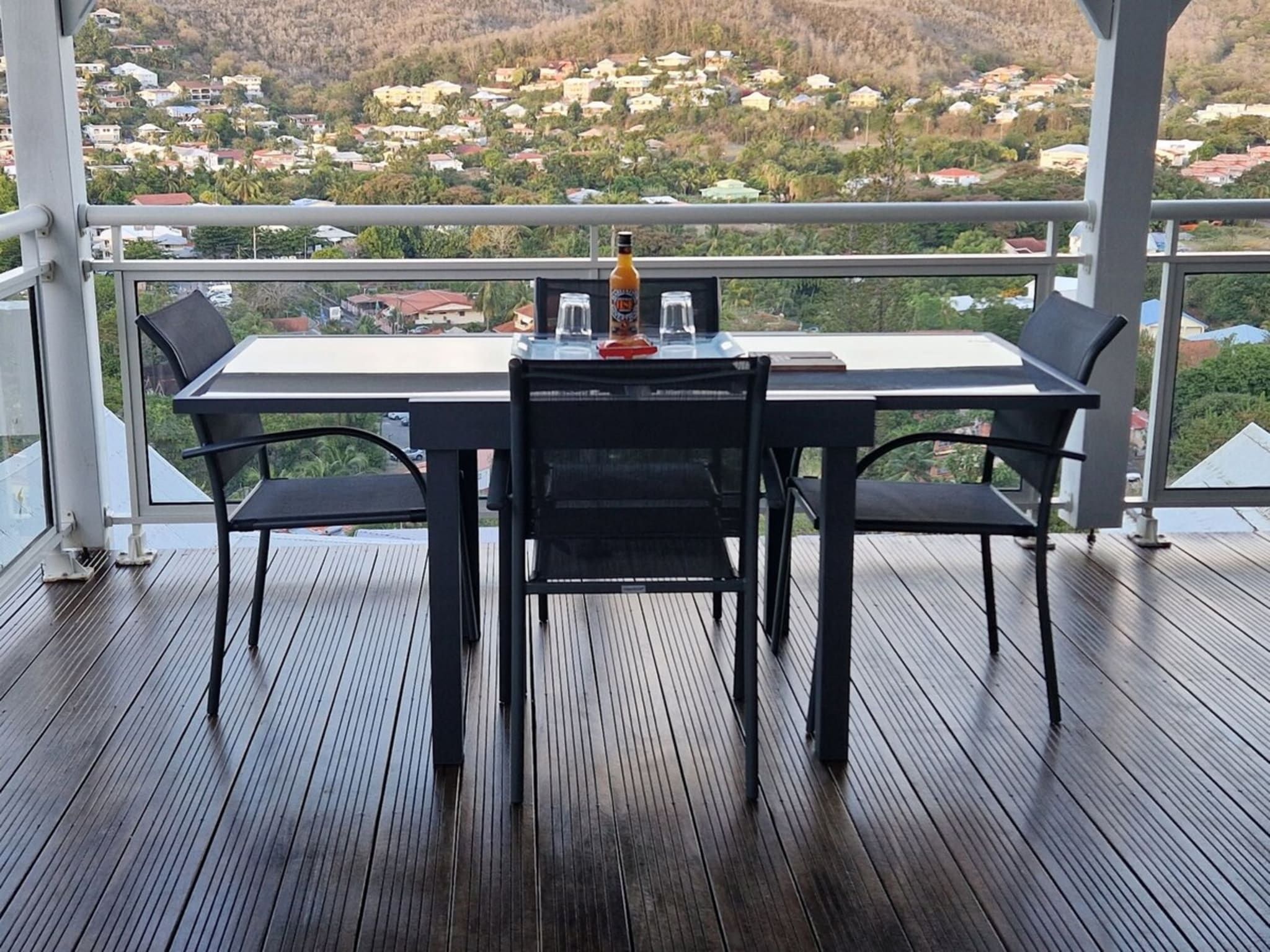 A balcony with a table and chairs, overlooking a residential area.