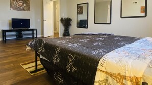 Une chambre à coucher avec un lit, un téléviseur posé sur un meuble et deux miroirs fixés au mur.