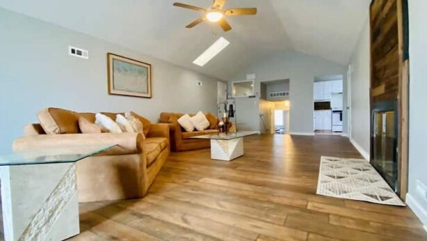 Un vaste salon doté d’un haut plafond, d’un plancher en bois et d’un ventilateur de plafond.