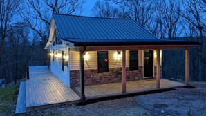 Een chalet met een houten terras, een fundering van steen en een metalen dak.