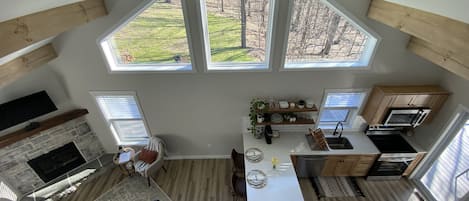 A modern kitchen with a dining area, large windows, and a stone fireplace.