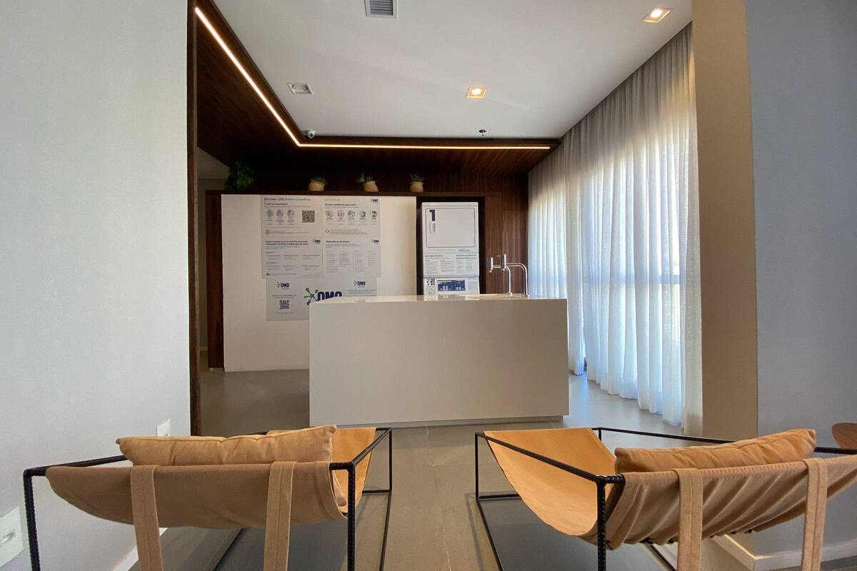 Un espace d’accueil moderne comprenant un bureau, deux chaises et une grande fenêtre avec des rideaux.