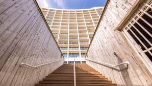 A set of wooden stairs leading up to a building with a grid-like facade.