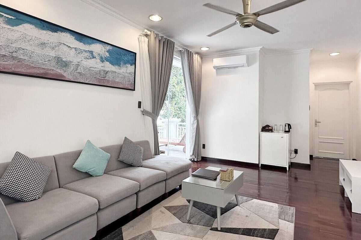 A modern living room with a grey sofa, a coffee table, and a ceiling fan.