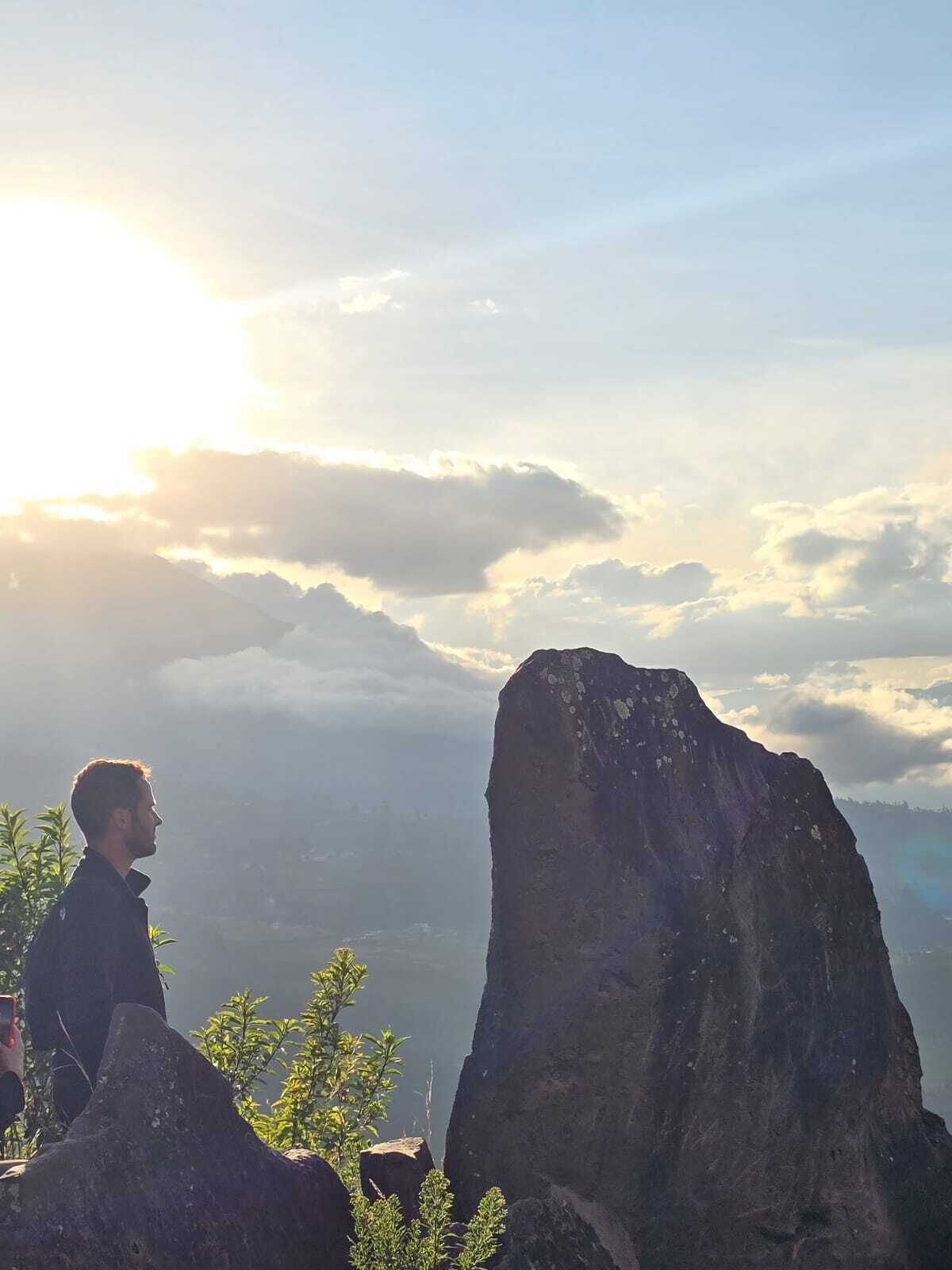 Una persona observa un paisaje montañoso con una formación rocosa destacada y vistas del valle.