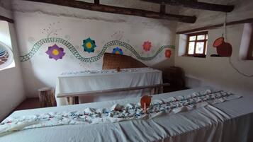 Una habitación con una cama, una mesita pequeña y un muro decorado con motivos florales coloridos.