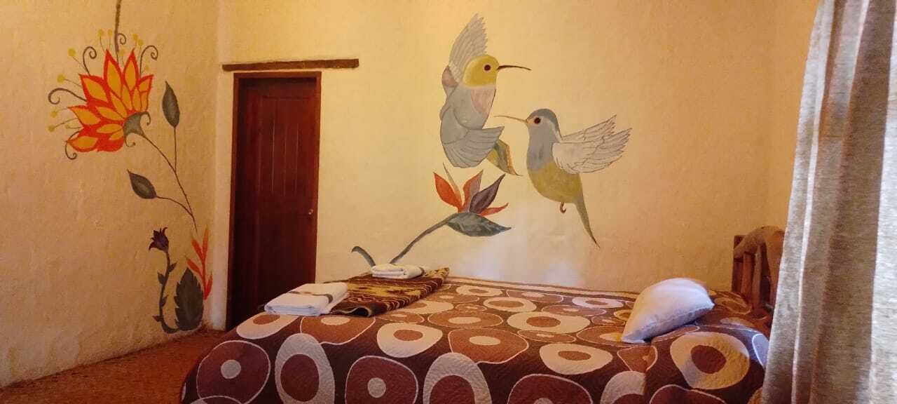 A bedroom with a bed, a nightstand, and a wall mural of birds.