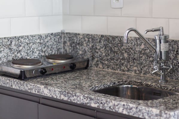 Uma cozinha com bancadas de granito, pia de aço inoxidável e fogão a gás.