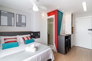 Habitació d'hotel moderna amb llit, escriptori i zona de banyera de dutxa.