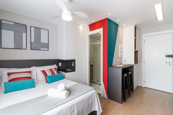 A modern hotel room with a bed, a desk, and a shower area.