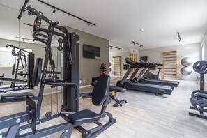 Uma academia com diversos equipamentos de exercícios, incluindo esteiras e máquinas de musculação, e um espelho na parede.