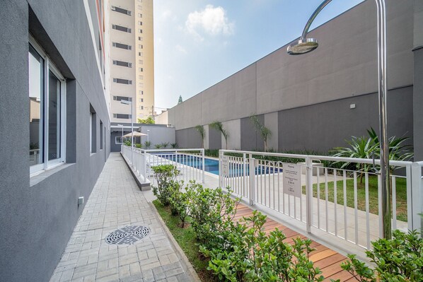 Ein modernes Gebäude mit Poolanlage, inklusive Weg, Geländer und Bepflanzung.