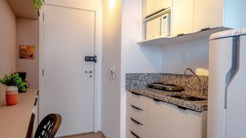 A compact kitchen with white cabinets, a granite countertop, and a built-in microwave.