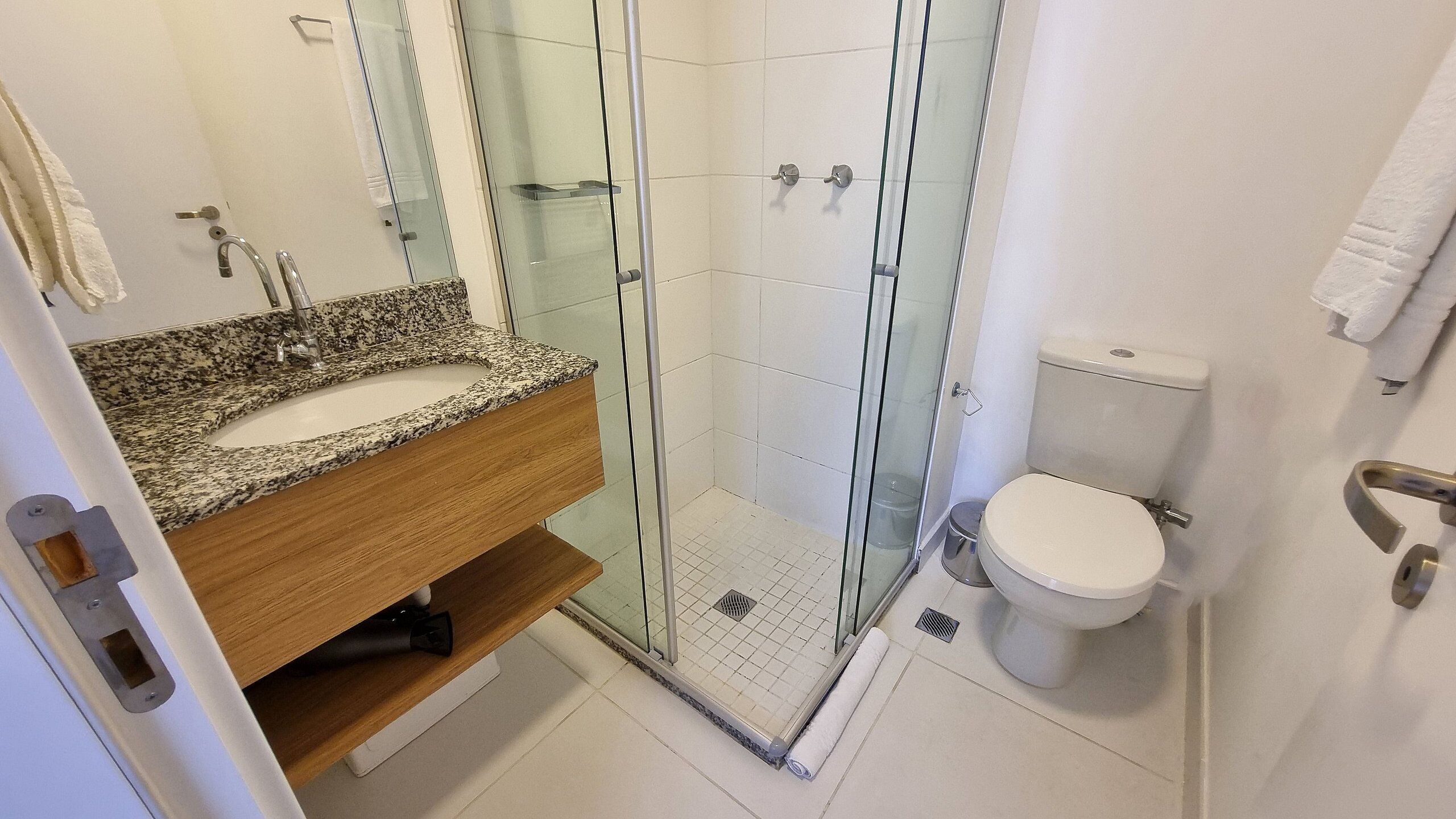 Une salle de bain avec un lavabo sur un plan de travail en granit, une douche à parois de verre et des toilettes.