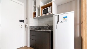 A compact kitchen with a white refrigerator, a microwave, and a granite countertop.