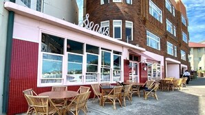Ein Restaurant mit Außenbereich, großen Fenstern und einer Ziegel-Fassade.