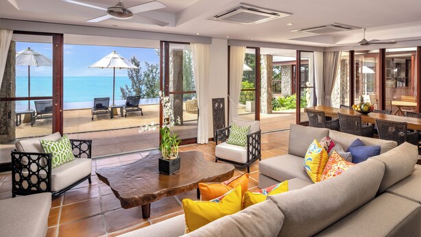 A spacious living area with a large window overlooking the sea, furnished with sofas, chairs, and a wooden coffee table. - Villa Horizon (Kamala)