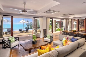 Amplia sala de estar con un gran ventanal con vistas al mar, amoblada con sofás, sillas y una mesa de centro de madera.