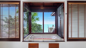 A bathroom with a large window, wooden blinds, and a bathtub. - Villa Horizon (Kamala)