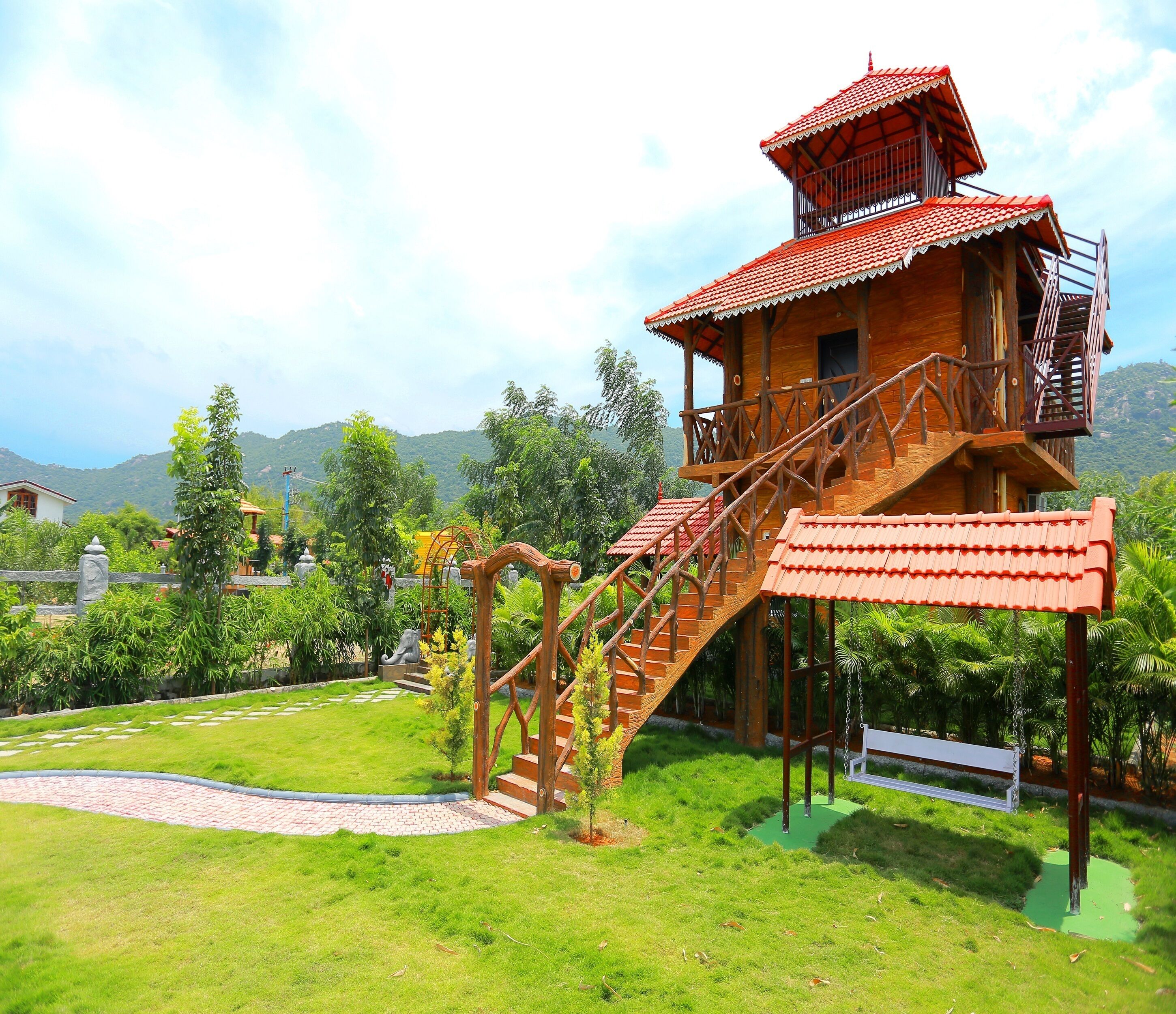 A wooden house with a red roof and a staircase leading to a balcony.