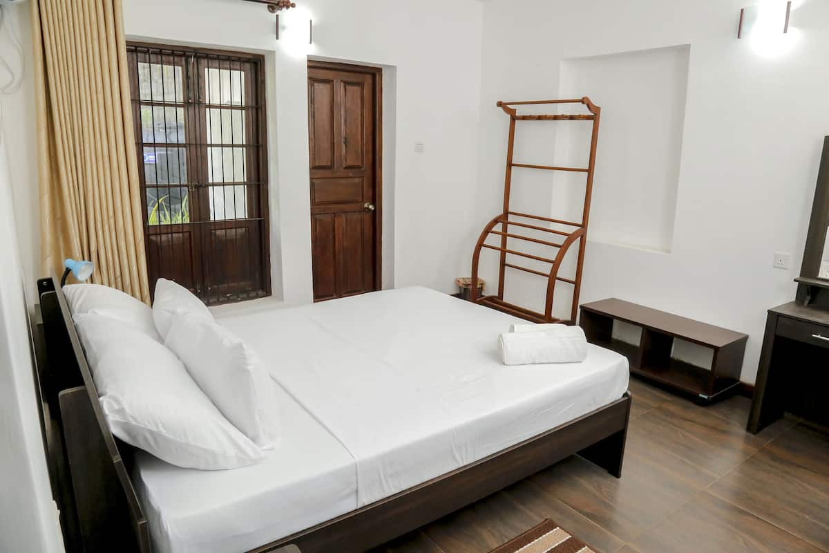 A bedroom with a single bed, a wooden ladder, a bench, a TV stand, and a door with a window.