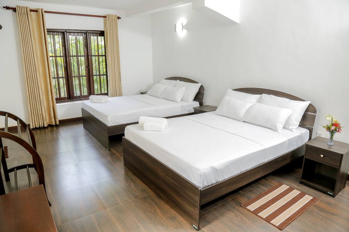 A hotel room with two beds, a desk, and a window with curtains.
