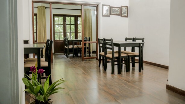 Un comedor con piso de madera, una mesa con sillas y vista a un balcón con cortinas a través de un ventanal.