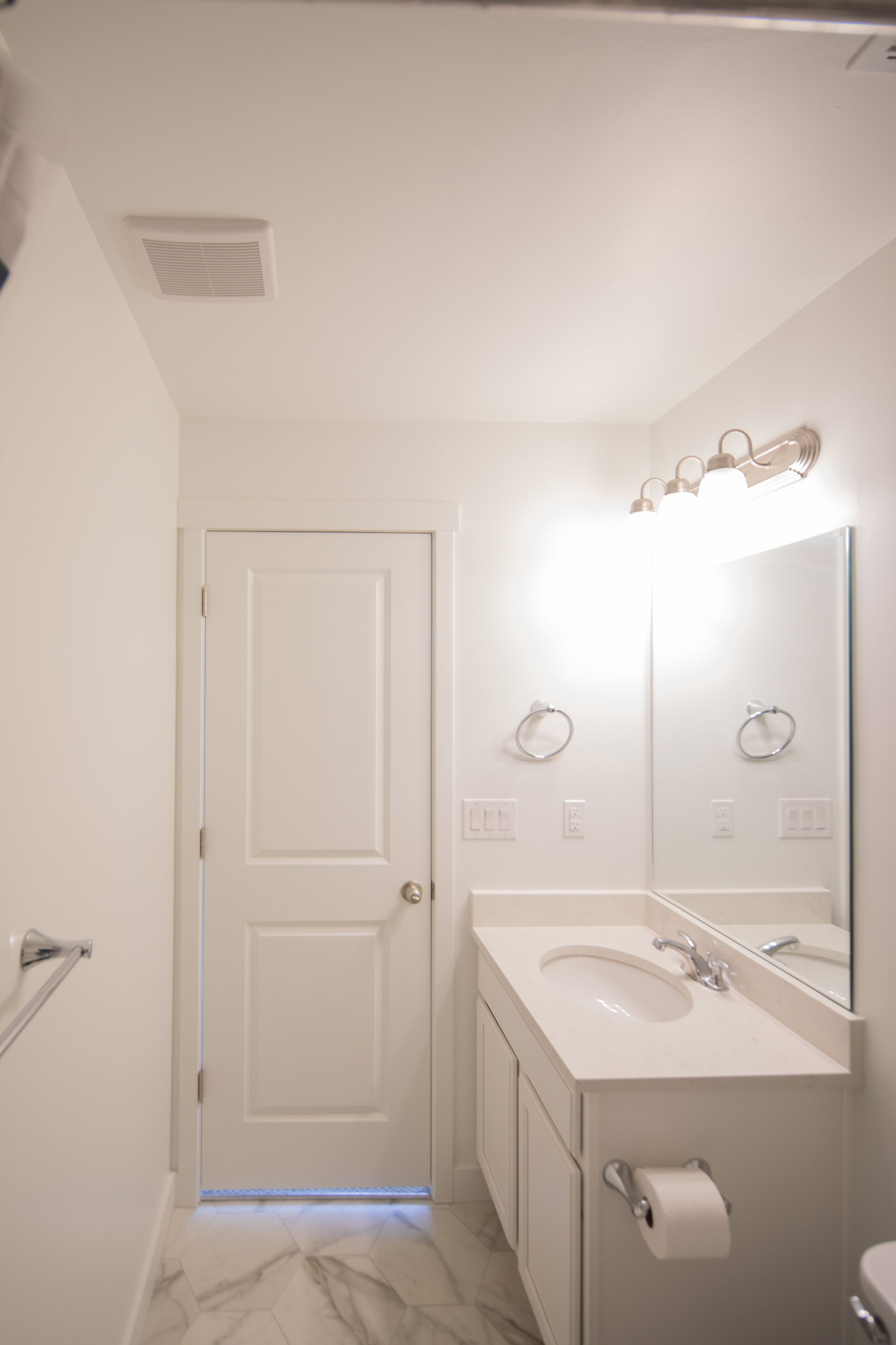 Un bagno con una porta bianca, un lavandino con specchio e un water.