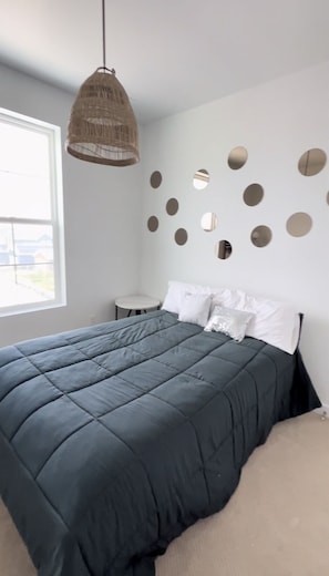 Une chambre avec un grand lit, une petite table ronde et un luminaire suspendu.