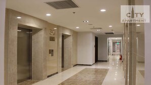 A modern hallway with elevators, a fire extinguisher, and a sign indicating the building is a City Apartment. - Kelly House at Vinhomes Central Park (Ho Chi Minh City)
